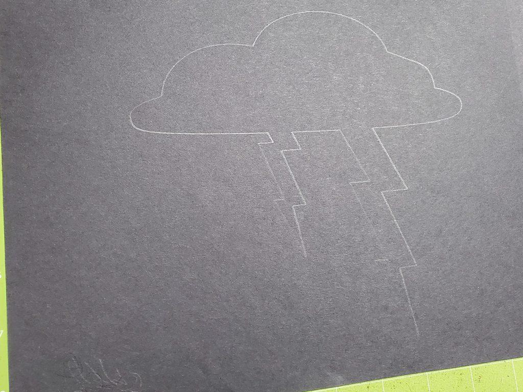 A lightning cloud shape traced onto black construction paper